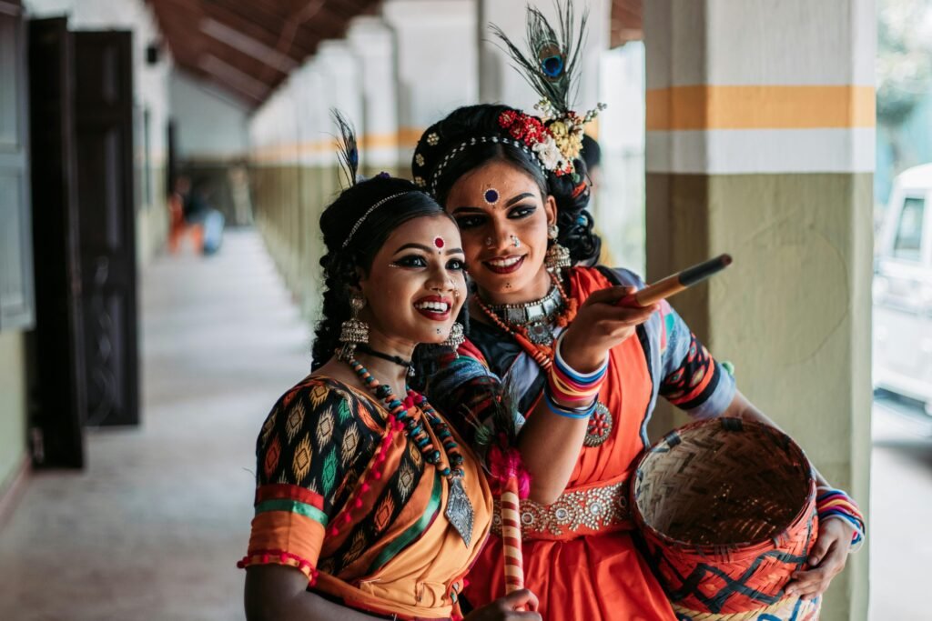 Two women in vibrant traditional attire share a joyful moment in a cultural dance setting.