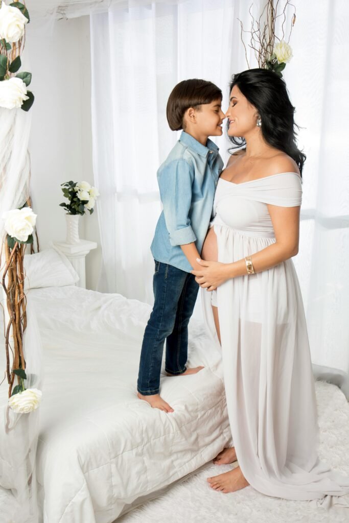 Pregnant woman and child share a tender moment in a beautifully decorated bedroom.