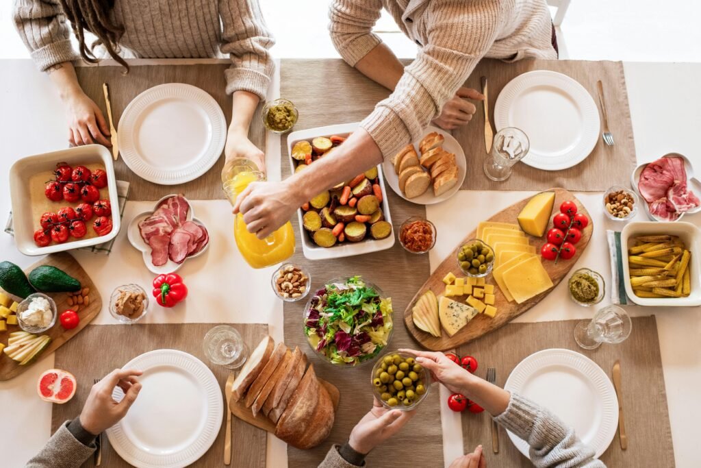 Aerial shot of a diverse brunch spread on a table with multiple hands serving food.