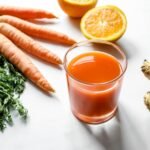 Fresh carrot ginger and orange juice surrounded by ingredients on a white background.