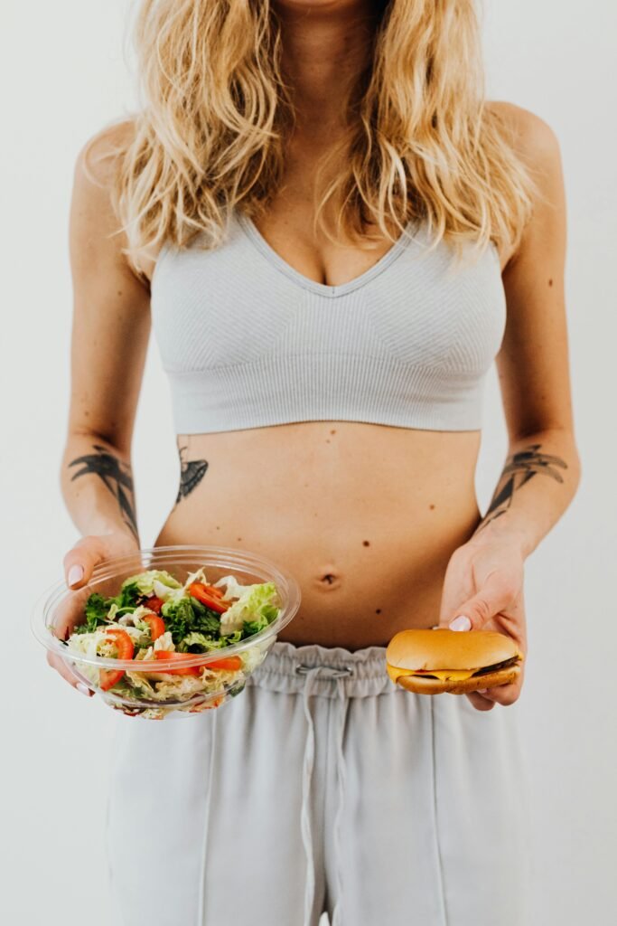 A woman deciding between a healthy salad and a burger, symbolizing diet and lifestyle choice.