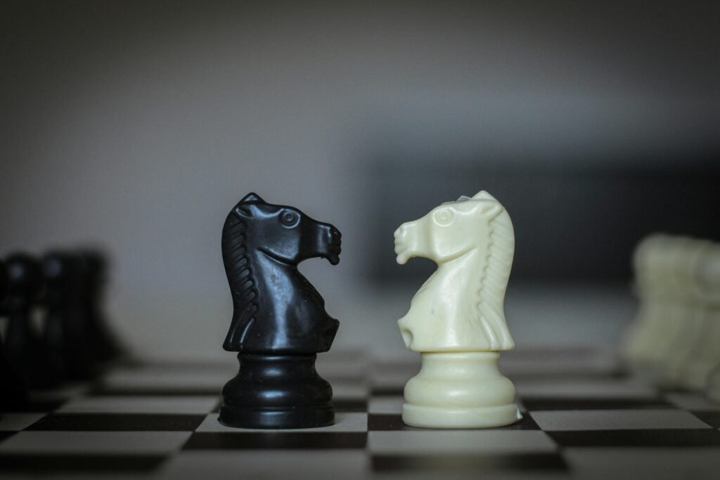 Dramatic close-up of black and white knight chess pieces face off, symbolizing strategic battle.
